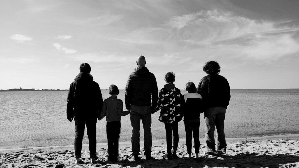 Familie in beliebiger Reihenfolge von hinten mit Blick aufs Meer